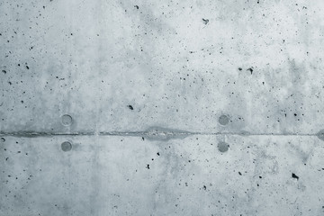 Gray concrete wall coarse facade made of natural cement with holes and imperfections separating layers as an empty rustic cold sterile texture background empty space.