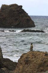 Fototapeta na wymiar A few beach stones one on top of the other next to a mountainous formation and next to the sea