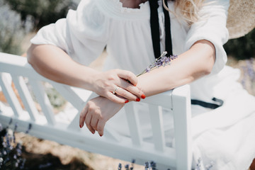 Woman in a white dress on a bench among lavender