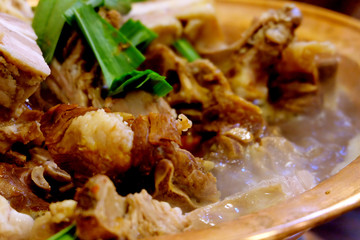 close up delicious Chinese hot pot. Large pieces of meat and green onion. Boiling soup water. Defocused background
