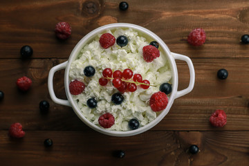 Bowl with cottage cheese and fresh berries on wooden table