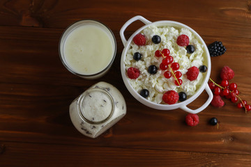 Composition with cottage cheese, fresh berries and yogurt on wooden table