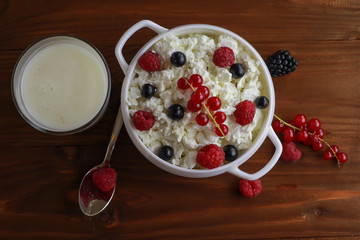 Composition with cottage cheese, fresh berries and yogurt on wooden table