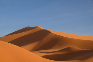 Fototapeta na wymiar brown Sahara Desert mountains under sunshine. Blue skyline. Near Merzouga in Morocco. wide angle