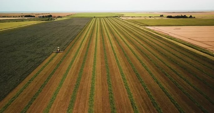 Drone shot diving in on a mower cutting a field of hay