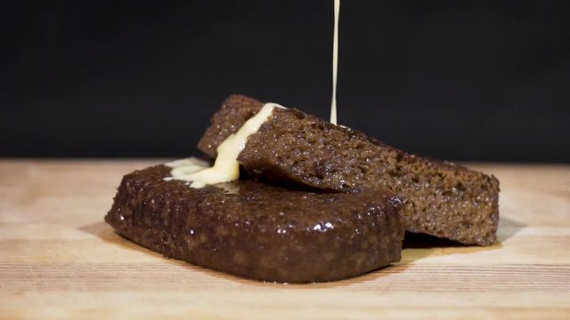 Slow motion close up shot of custard being poured onto steaming hot Malva pudding