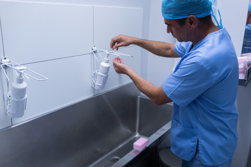 Male surgeon washing hands in sink at hospital