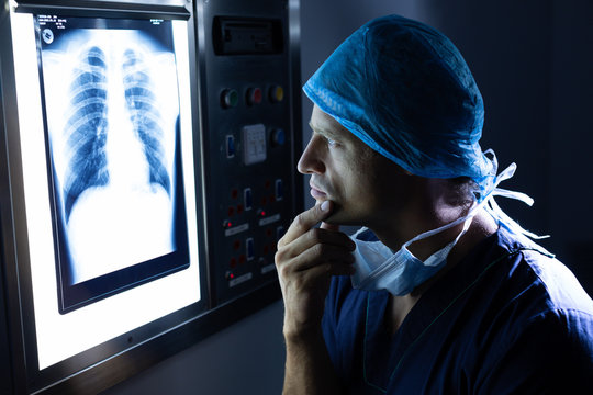 Male surgeon examining x-ray on light box in operation theater