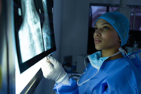 Female surgeon examining x-ray on light box in operation theater