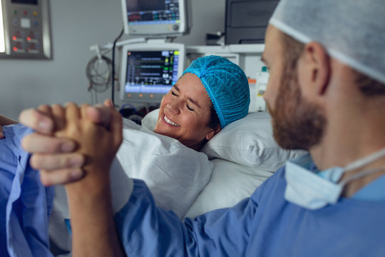 Man comforting pregnant woman during labor in operating room