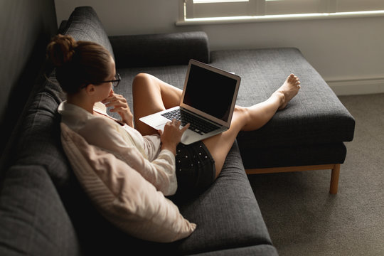 Woman using laptop on a sofa in living room