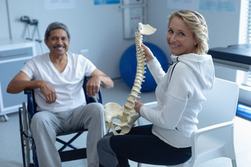 Female physiotherapist explaining spine model to male patient