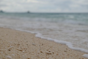 extreme close up sands and stones details on beach. Blur green sea horizon and waves background. In Boracay Island Philippines