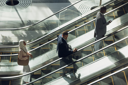 Business people using escalators in modern office 