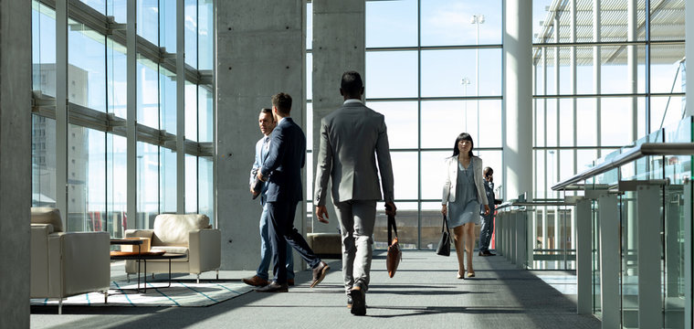 Businessman Walking Down The Hallway In Modern Office