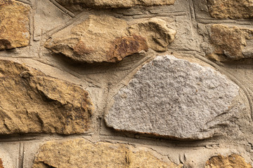 Background in the form of a fragment of a stone wall with textured stones from a light brown rubble