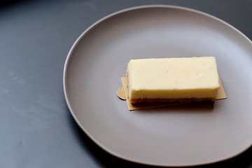 close up a brown slice of mousse cake in red-brown plate. Gray table background