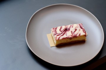 close up a slice of berry mousse cake in red-brown plate. Gray table background