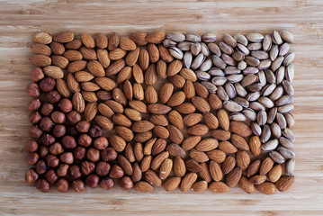 Nuts hazelnuts, almonds, pistachios laid out in the form of a rectangle on a light brown background