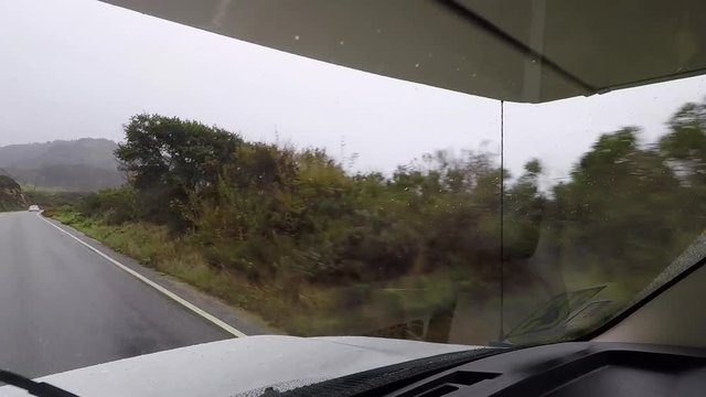 Windshield POV of an RV moving fast on a rainy day while driving.