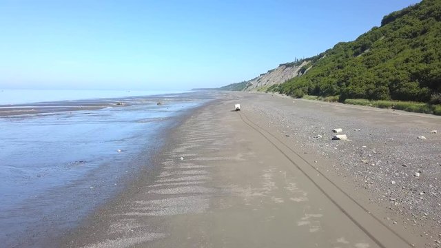 Aerial, drone shot, following a 4x4 overland RV, driving on a beach, at low tide, in Deep Creek State Recreation Area, Ninilchik, Alaska, USA