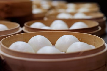 Close up white bean buns in steamers. Traditional Chinese dim sum. Blur perspective background