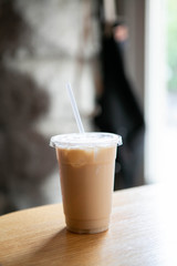 Iced Chai Latte in To Go Cup on Table, Coffee on Wooden Bar in Cafe, Close up photo