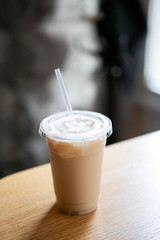 Iced Chai Latte in To Go Cup on Table, Coffee on Wooden Bar in Cafe, Close up photo