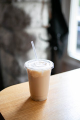 Iced Chai Latte in To Go Cup on Table, Coffee on Wooden Bar in Cafe, Close up photo