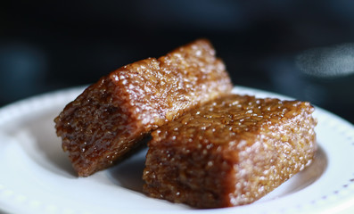 Wajik on black background.  Wajik is traditional snack made with steamed glutinous (sticky) rice and further cooked in palm sugar, coconut milk, and pandan leaves.
