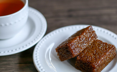 Wajik and a cup of tea on wood background.  Wajik is traditional snack made with steamed glutinous (sticky) rice and further cooked in palm sugar, coconut milk, and pandan leaves.