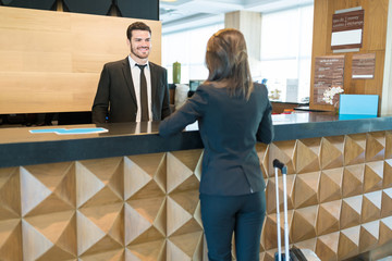 Entrepreneur Booking Room While Talking With Hotel Staff In Lobby