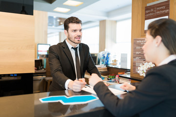 Clerk And Entrepreneur Standing At Counter In Hotel Lobby