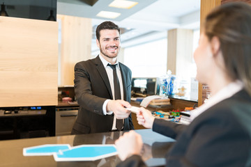 Businesswoman Paying Through Card At Front Desk In Hotel