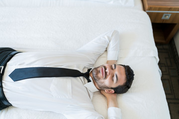 Businessman Resting On Bed In Hotel