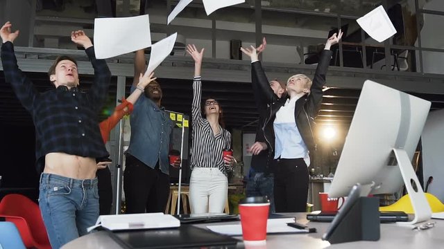 Group of business people from different ethnic backgrounds rejoices and celebrates their success in the financial and economic fields, throwing up paper documents