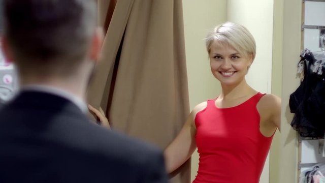 Couple In The Fitting Room Of Women's Store. The Girl Shows Clothing To Guy