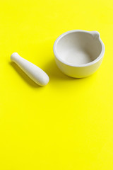 Mortar and pestle on yellow background.