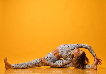 Young attractive woman practicing yoga, working out, wearing sportswear, full length on a yellow...