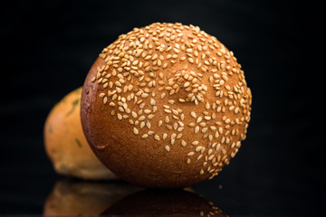 Bun with sesame seeds on a black background.