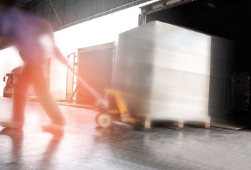 motion blur of worker unloading cargo pallet out of a truck