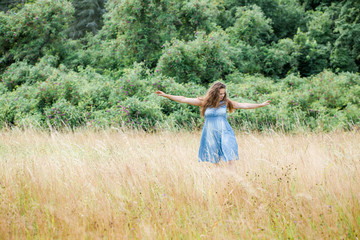 Naklejka na ściany i meble girl with beautiful hair in a blue dress walks across the field