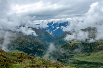 Fototapeta na wymiar Green valley surrounded by mountains in clouds, Choquequirao trek between Yanama and Totora, Peru