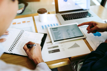 Business partnership coworkers analysis cost work progress and using a tablet to graph company...