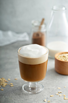 Oat milk latte with thick foam in a glass