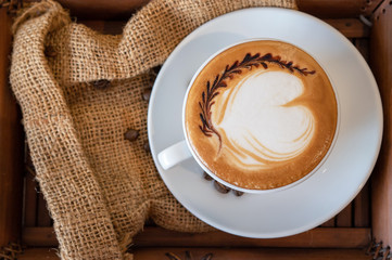 Hot coffee, a cup of cappuccino with latte art heart on wooden background. White ceramic cups.Love coffee.