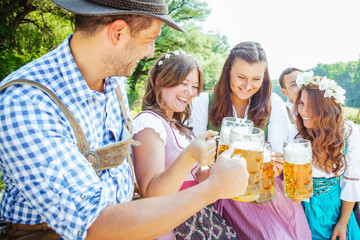 Five friends, men and women, having fun on Bavarian RIver and clinking glasses with beer