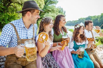 Five friends, men and women, having fun on Bavarian RIver and clinking glasses with beer