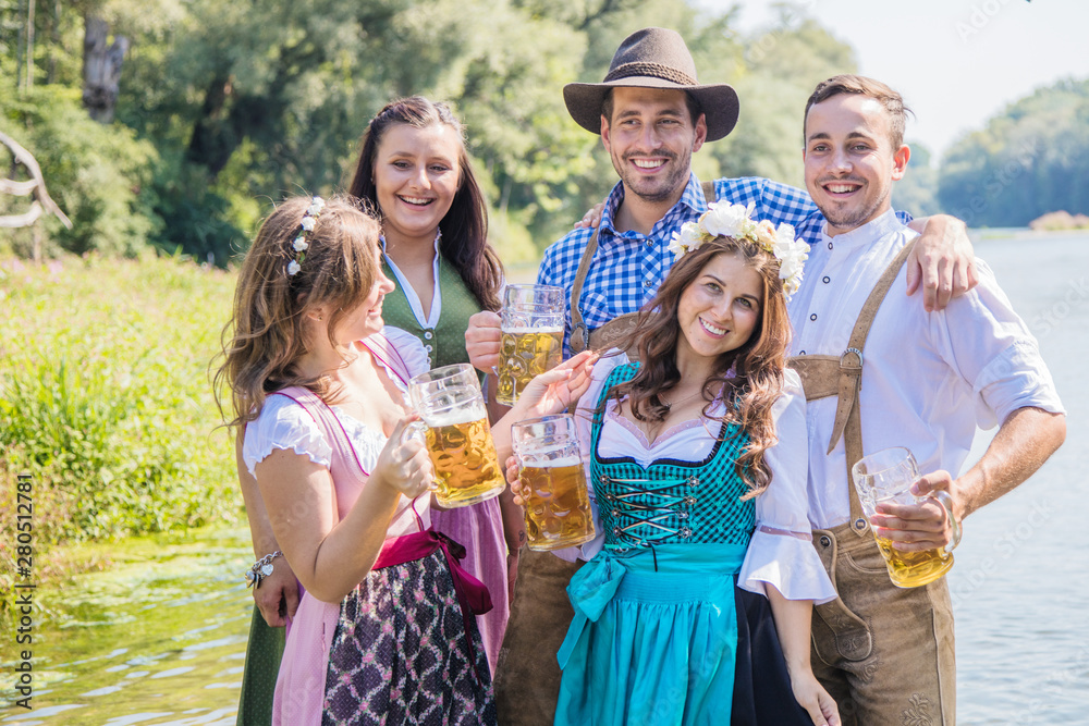 Wall mural Freunde in bayerischen Tracht feiern an der Isar und trinken Bier. Oktoberfest München