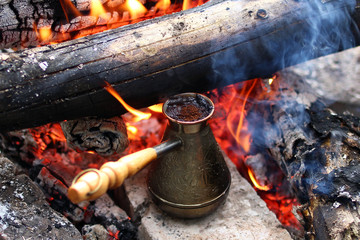 Metal cezve with hot coffee on a bonfire.